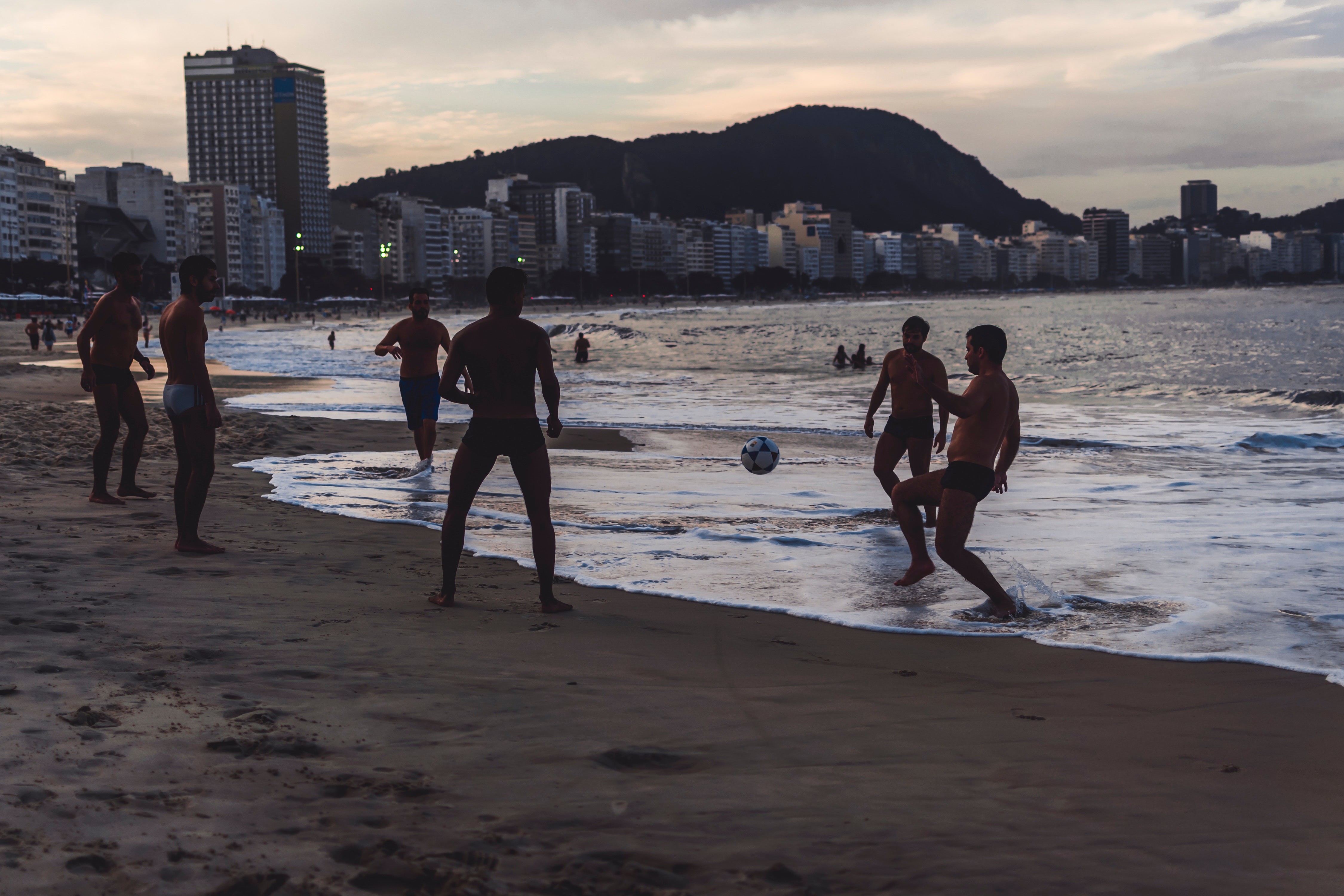men-playing-ball-by-the-seashore-2559997